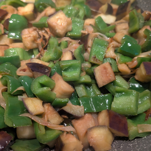 Cubed aubergine turning golden as it cooks with the peppers